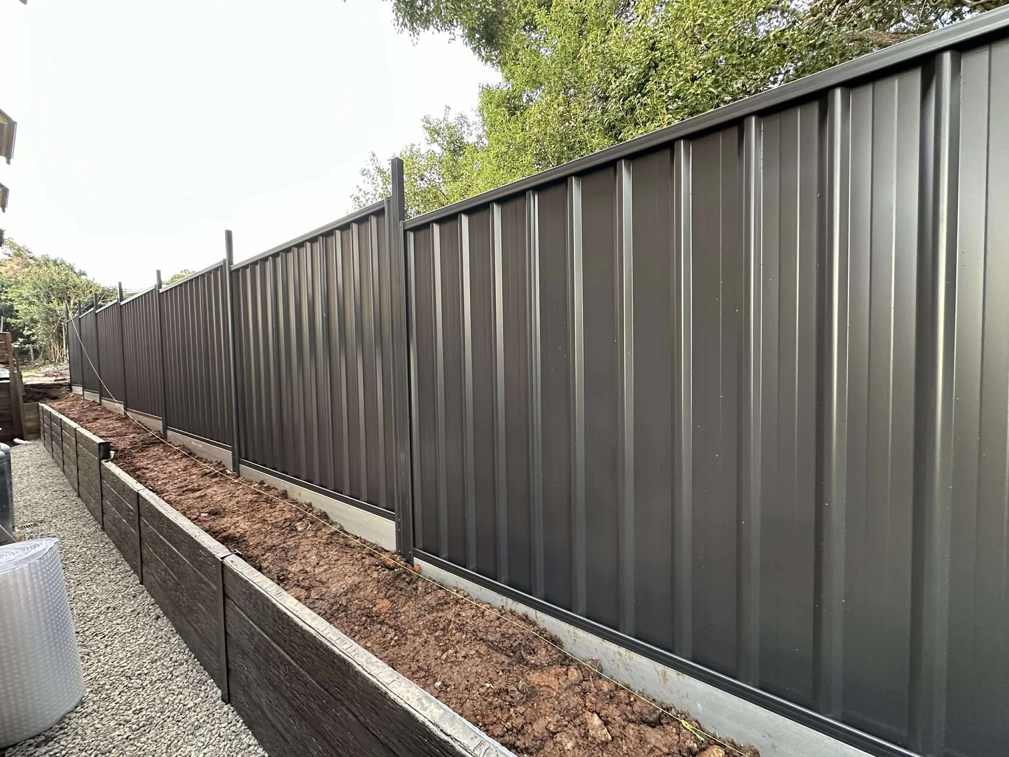 Timber-style modular block retaining wall along a garden bed